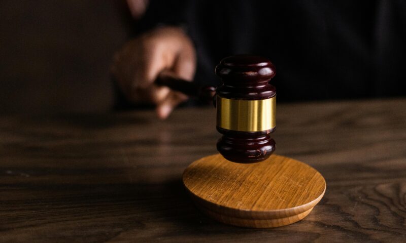 a person holding a wooden gavel on a wooden table