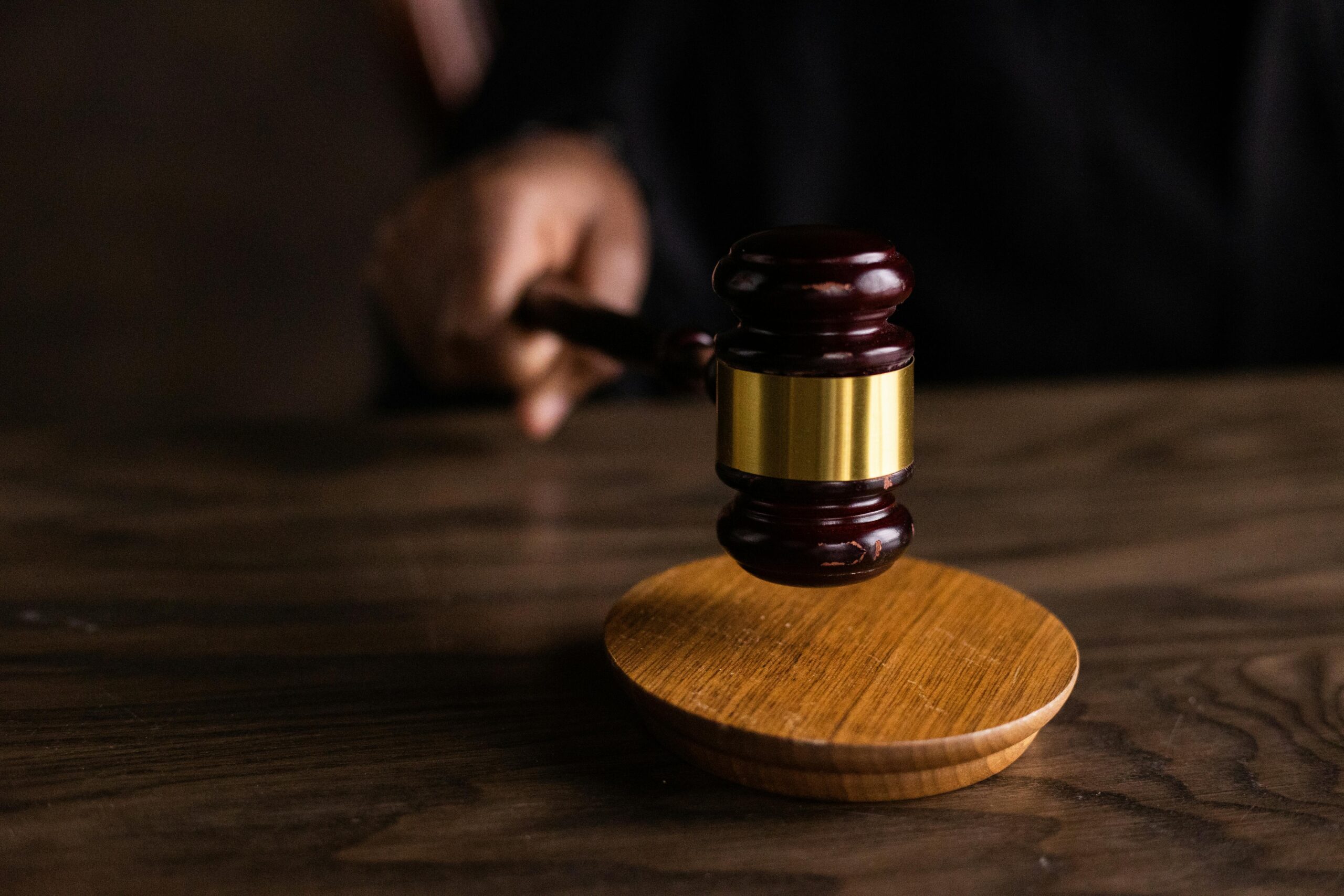 a person holding a wooden gavel on a wooden table