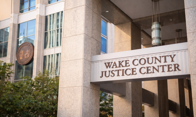 Front entrance of the Wake County Justice Center in Raleigh, North Carolina, with courthouse columns and building signage visible.